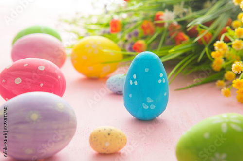 Easter eggs with wild flowers on a wooden pink table background