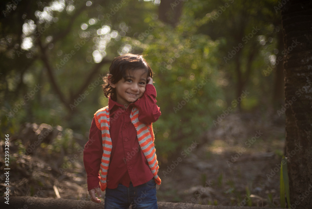 Portrait of an Indian brunette baby boy in winter wear enjoying himself in a field on a winter afternoon in green natural background. Indian lifestyle and childhood. Portrait of an Indian brunette baby boy in winter wear enjoying himself in a field on a winter afternoon in green natural background. Indian lifestyle and childhood.