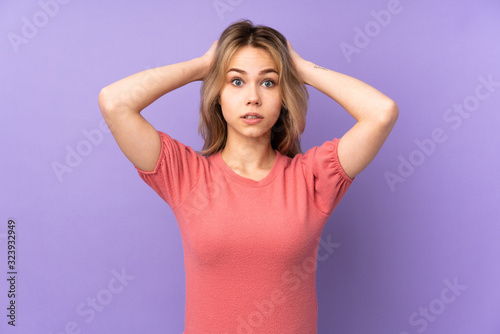 Teenager Russian girl isolated on purple background frustrated and takes hands on head
