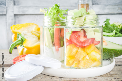 Healthy take-away lunch jar. Vegan vegetable salad in glass jars, with sliced fresh vegetables. Detox, raw eating and zero waste lunch concept photo