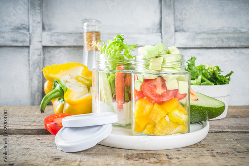 Healthy take-away lunch jar. Vegan vegetable salad in glass jars, with sliced fresh vegetables. Detox, raw eating and zero waste lunch concept photo