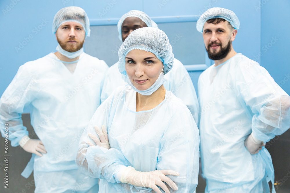 Portrait of a team of doctors in uniform and medical masks after completion of a surgical operation Portrait of a team of doctors in uniform and medical masks after completion of a surgical operation