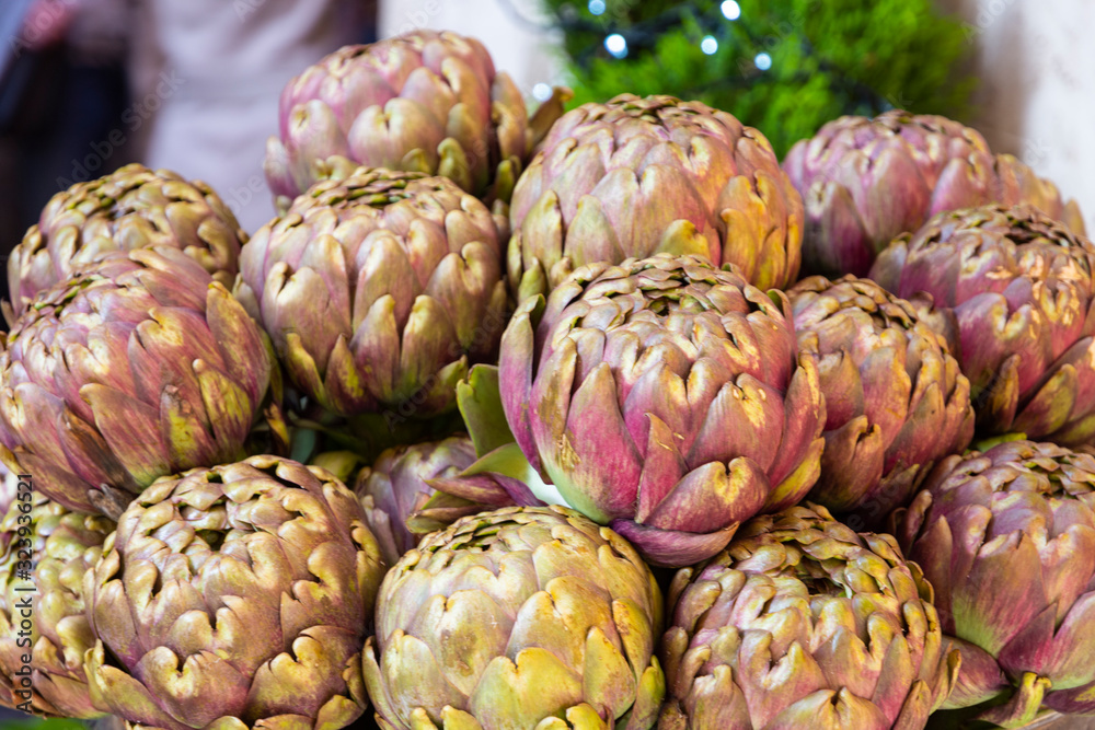 Obraz premium Fresh big Romanesco artichokes, green purple flower heads on a market place