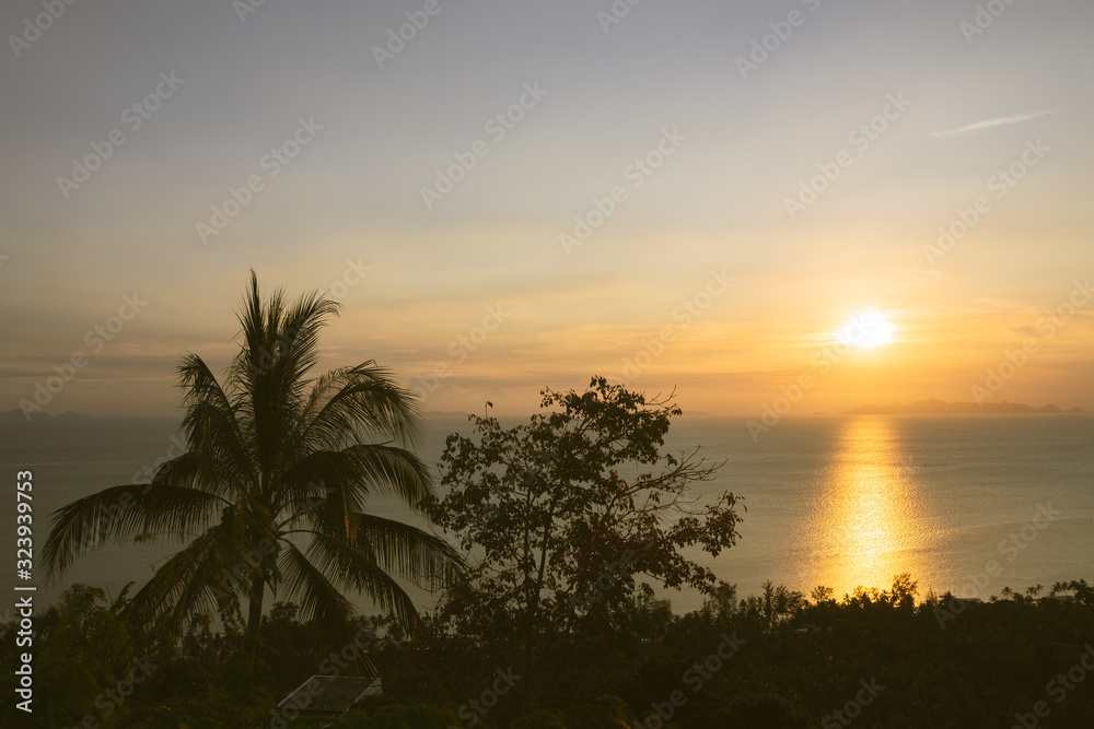 Beautiful yellow or golden sunset on the sea in Thailand on Koh Samui. Calm and low tide. Panorama of how to set the sun. Palms and hills and boats