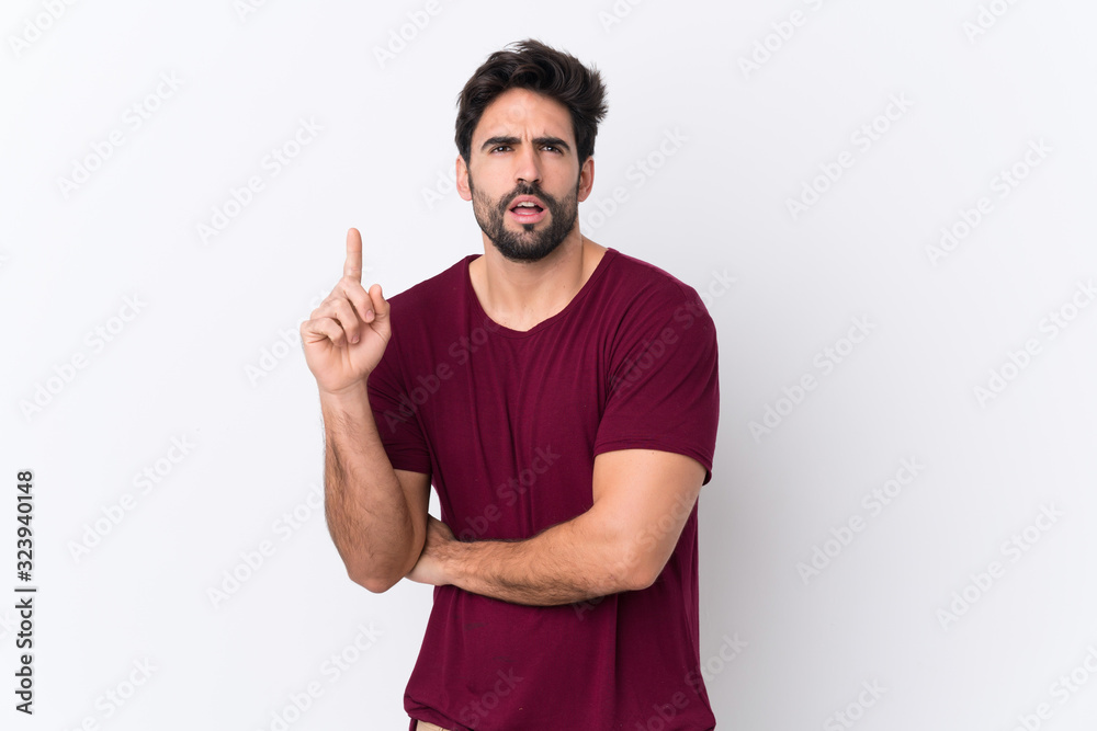 Young handsome man with beard over isolated white background thinking an idea pointing the finger up Young handsome man with beard over isolated white background thinking an idea pointing the finger up