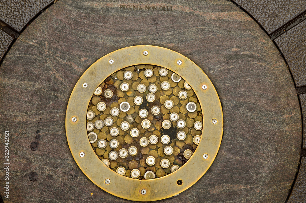 Goes, the netherlands, August 2019. In the streets of the historic center, a manhole cover covered with euro coins minted. An engraving reports the ancient saying: money has no smell.