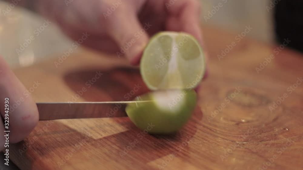 male hand slices lime, on brown board closeup, 2019 male hand slices lime, on brown board closeup, 2019