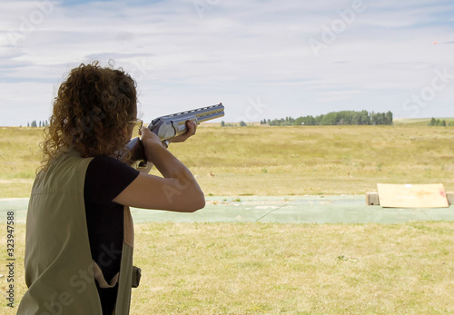 mujer joven practicando el deporte de tiro al plato al aire libre