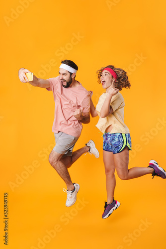 Portrait of athletic couple smiling and taking selfie photo on cellphone