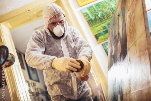 Restorer working on the painting at restoration workshop photo