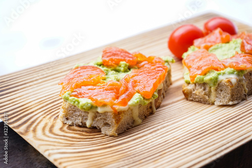Sandwich with avocado and smoked salmon on a wooden board.