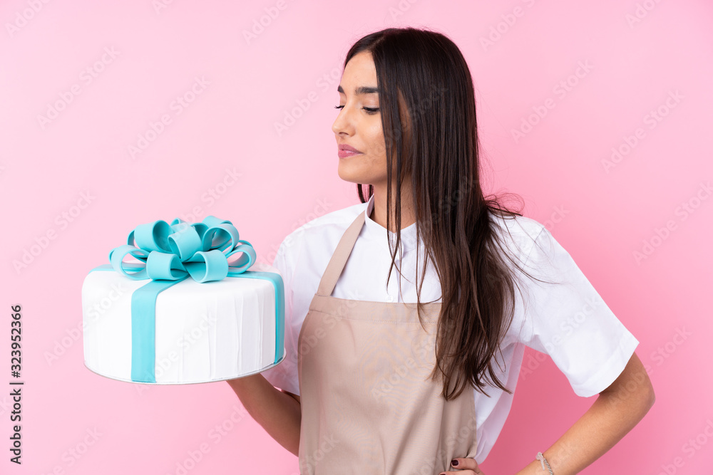 Young woman with a big cake over isolated background Young woman with a big cake over isolated background