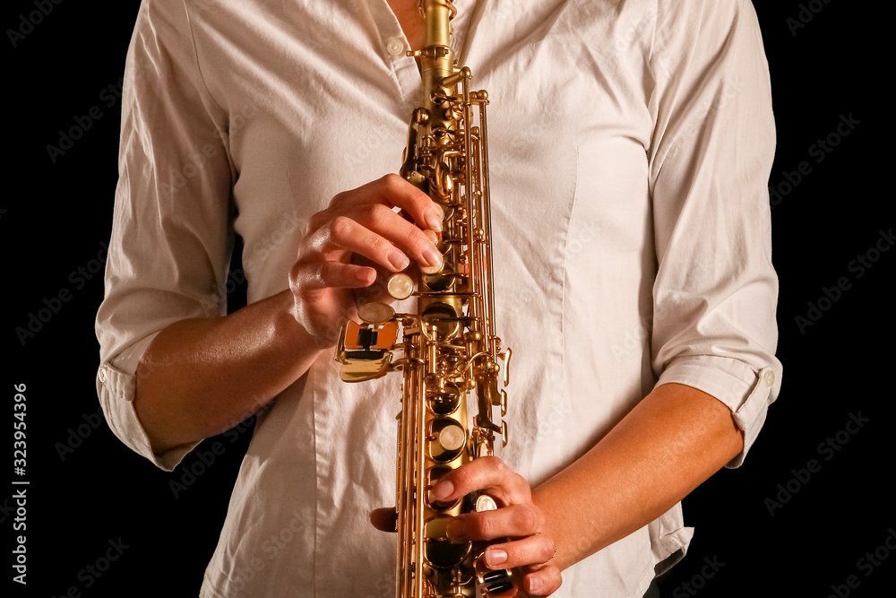 Fototapeta premium soprano saxophone in the hands of a girl on a black background
