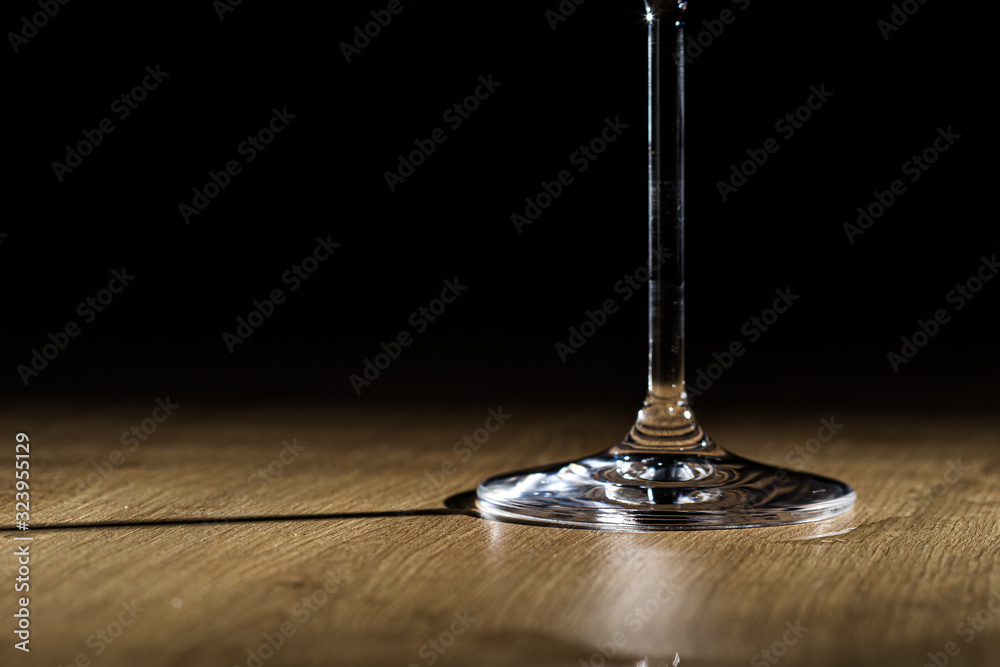 Wineglass foot shining on a wooden plank surface isolated on a black background Wineglass foot shining on a wooden plank surface isolated on a black background