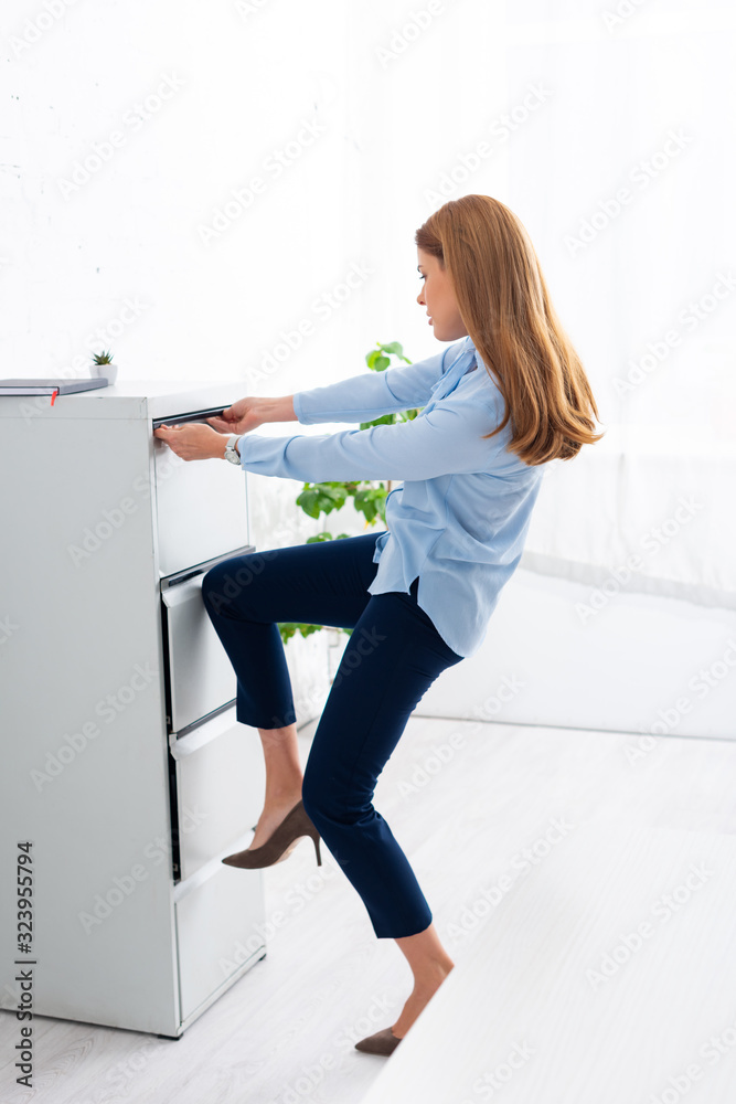 Side view of businesswoman trying to opening cabinet driver in office Side view of businesswoman trying to opening cabinet driver in office