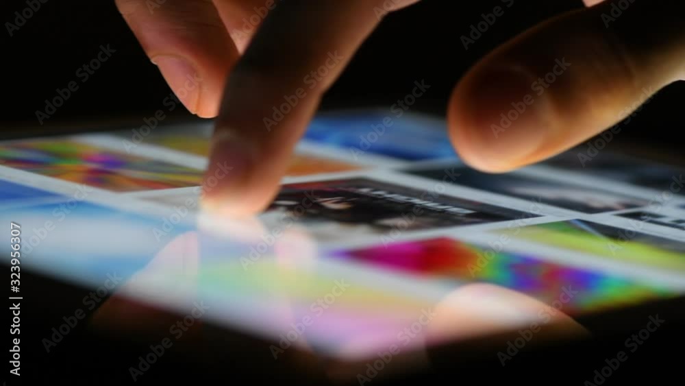 Illuminated fingers tapping and scrolling on digital table in dark Illuminated fingers tapping and scrolling on digital table in dark