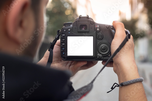 Young photographer looking at his photos on the street