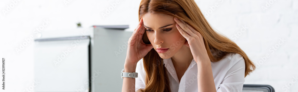 Panoramic shot of pensive businesswoman in hands near head in office Panoramic shot of pensive businesswoman in hands near head in office