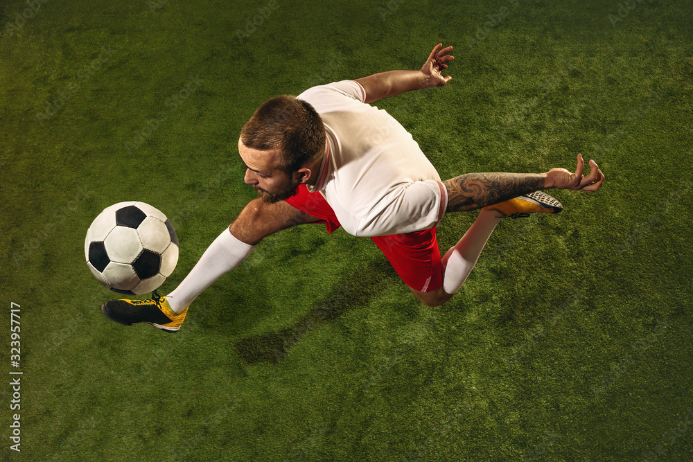 Top view of caucasian football or soccer player on green background of grass. Young male sportive model training, practicing. Kicking ball, attacking, catching. Concept of sport, competition, winning. Top view of caucasian football or soccer player on green background of grass. Young male sportive model training, practicing. Kicking ball, attacking, catching. Concept of sport, competition, winning.
