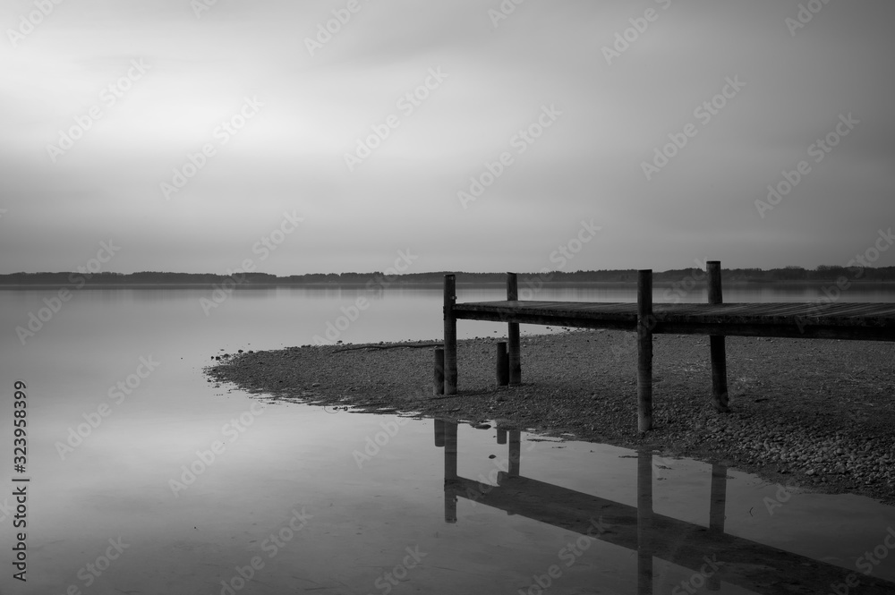 Langzeitbelichtungsaufnahme von einem Bootssteg am See in Schwarz-Weiß