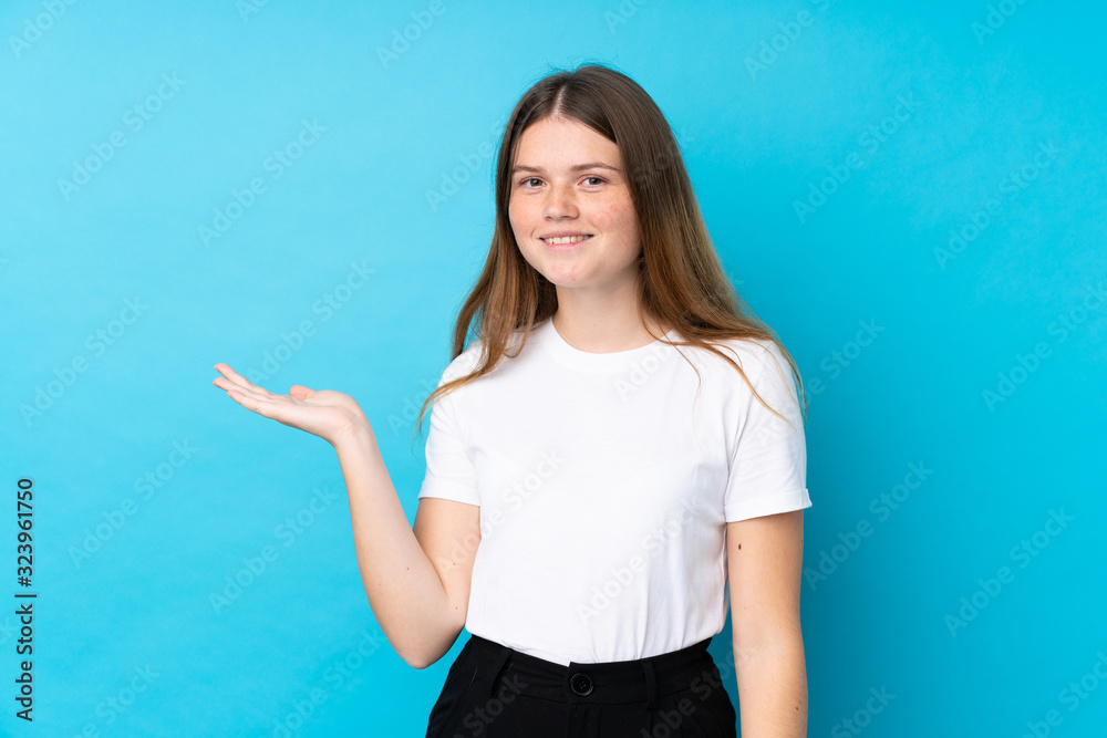 Ukrainian teenager girl over isolated blue background holding copyspace imaginary on the palm Ukrainian teenager girl over isolated blue background holding copyspace imaginary on the palm
