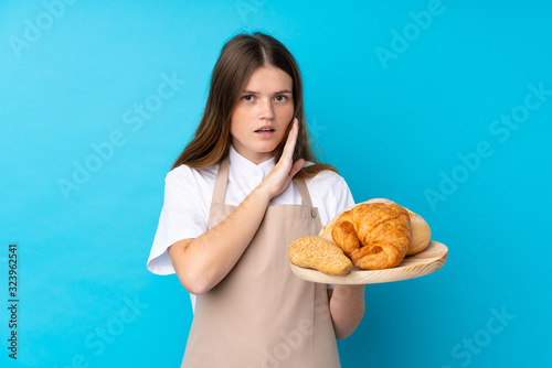 Ukrainian teenager chef uniform. Female baker holding a table with several breads whispering something