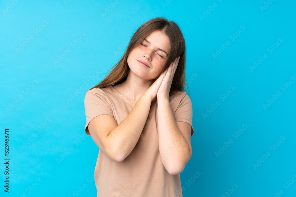 Ukrainian teenager girl over isolated blue background making sleep gesture in dorable expression Ukrainian teenager girl over isolated blue background making sleep gesture in dorable expression