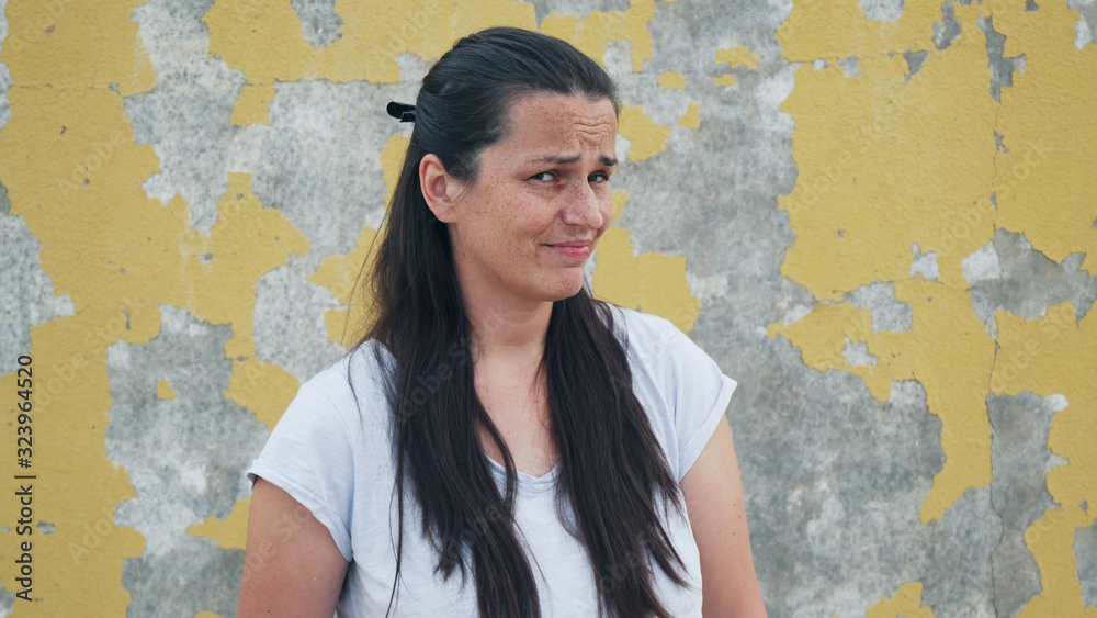 Obraz premium Portrait of handsome girl with freckles grimacing in front of wall