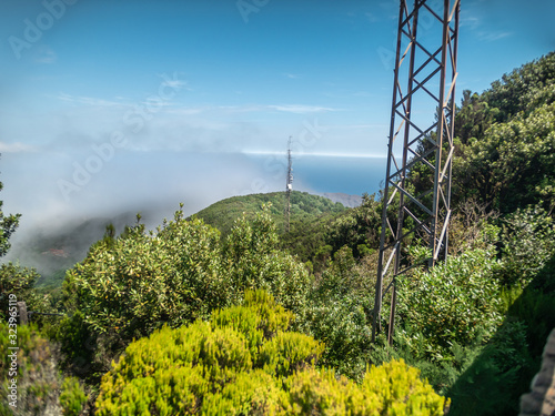 Image of metal telecommunication towers for TV or radio on the high mountain overgrown with jungle forest