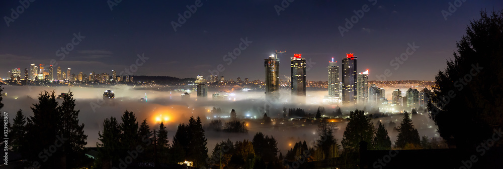 Fototapeta premium Burnaby, Vancouver, Kolumbia Brytyjska, Kanada. Piękny panoramiczny widok z lotu ptaka na nowoczesne miasto w nocy pokryte mgłą przed wschodem słońca zimowy poranek.