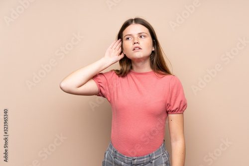 Ukrainian teenager girl over isolated background listening something