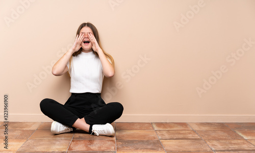 Ukrainian teenager girl sitting on the floor shouting and announcing something