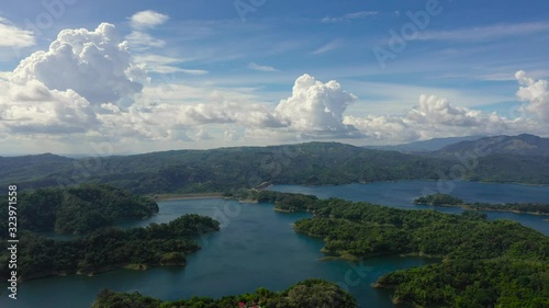 Clouds over a blue lake among green hills and mountains covered with rainforest. Aerial view: Pantabangan Lake. Philippines, Luzon.