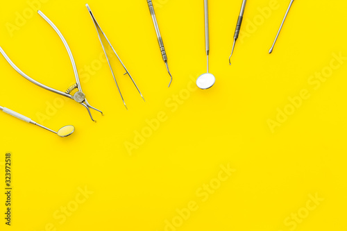 Stomatological tools on dentist's desk on yellow background top-down pattern frame copy space