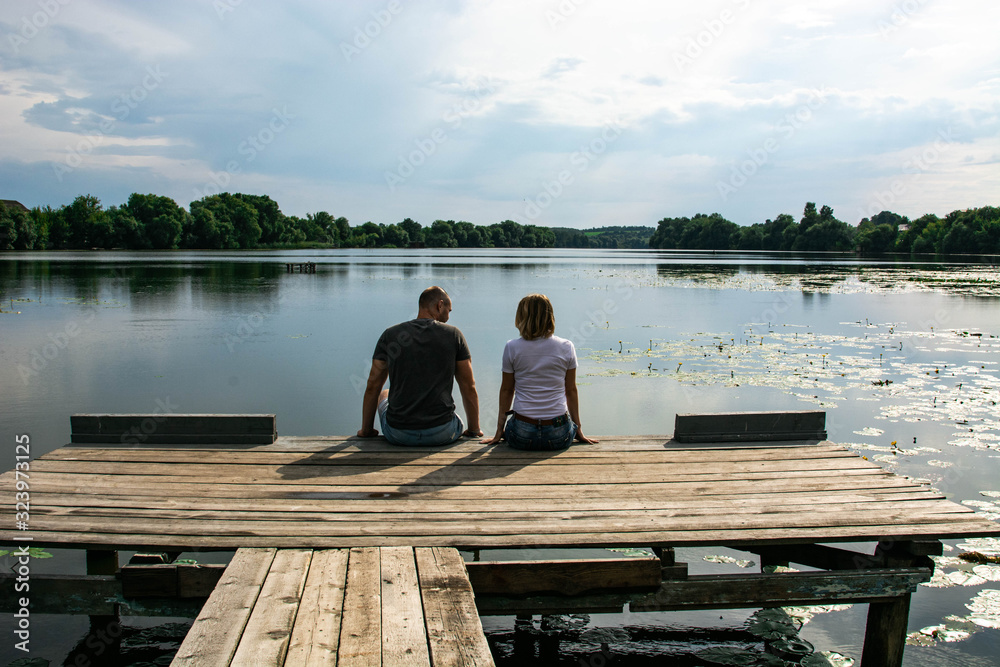 Love Couple Sitting on the Wooden Breakwater Love Couple Sitting on the Wooden Breakwater