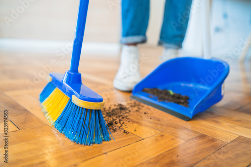 Latin man sweeping wooden floor with broom at home. photo