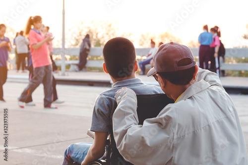 Portrait of Disabled child on wheelchair and father, Public bridge background with blurry, Special children’s enjoying outdoor activity at a normal life,,Happy disability kid concept.