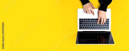 Person using a laptop computer on a solid color background