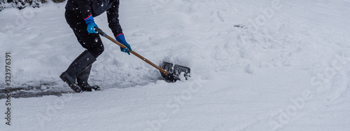 Young man shoveling snow from the walking path in winter. photo