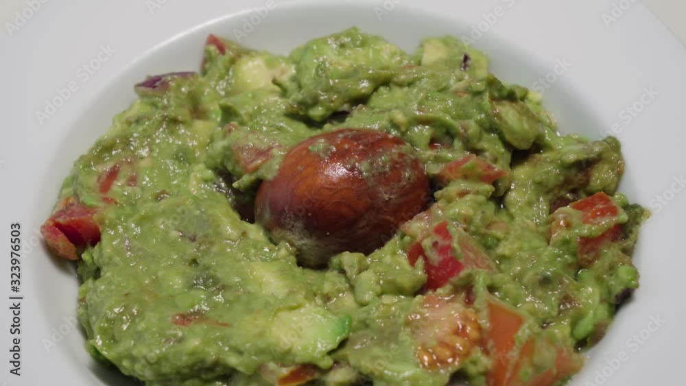 Tilt Up, Bowl of Fresh Guacamole with Avocado Pit, Closeup Tilt Up, Bowl of Fresh Guacamole with Avocado Pit, Closeup