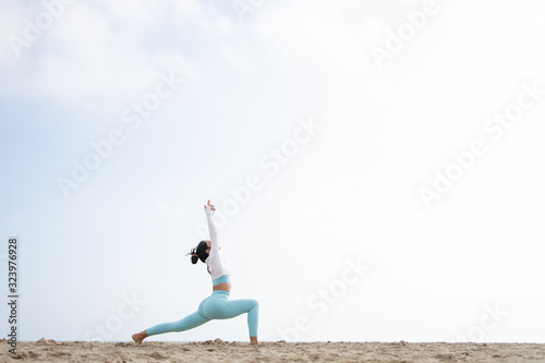 Fit girl doing yoga in the beach by the sea on a sunny day © Alvaro
