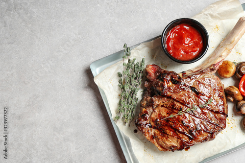 Delicious grilled ribeye with garnish on light table, top view. Space for text photo