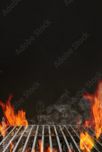 Hot empty barbecue BBQ grill with bright flaming fire, ember charcoal and smoke on black background. Waiting for the placement of your food. Close up