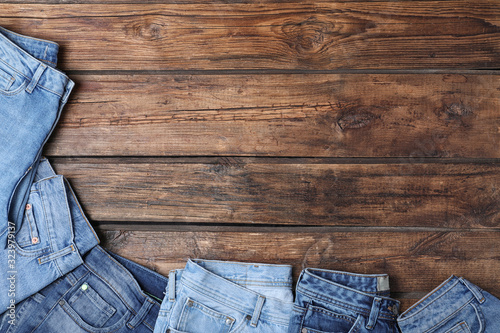Collection of stylish jeans on wooden background, flat lay. Space for text