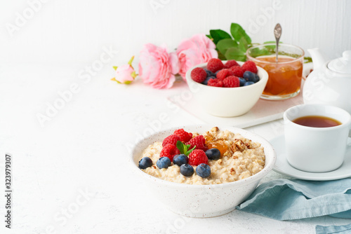 Oatmeal porridge with blueberry, raspberries, jam and nuts, side view, copy space,