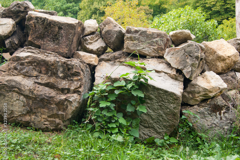 A fence of huge stone boulders laid on top of each other on a mountain slope against the backdrop of a mountain landscape. A fence of huge stone boulders laid on top of each other on a mountain slope against the backdrop of a mountain landscape.