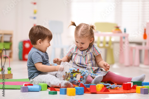 Cute little children playing together on floor at home