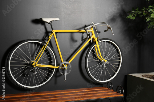 Yellow bicycle hanging on black wall indoors