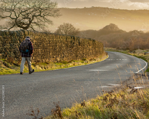 A senior strides out for a sunny early morning walk along the road across Baildon Moor photo