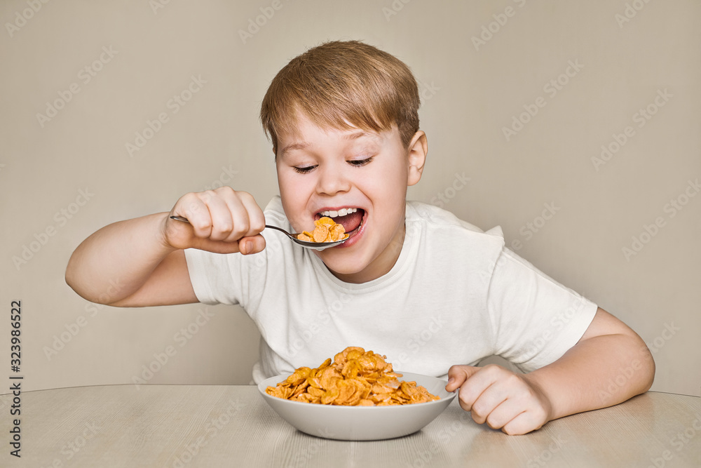 The boy at the table enjoys eating breakfast cereal with milk The boy at the table enjoys eating breakfast cereal with milk